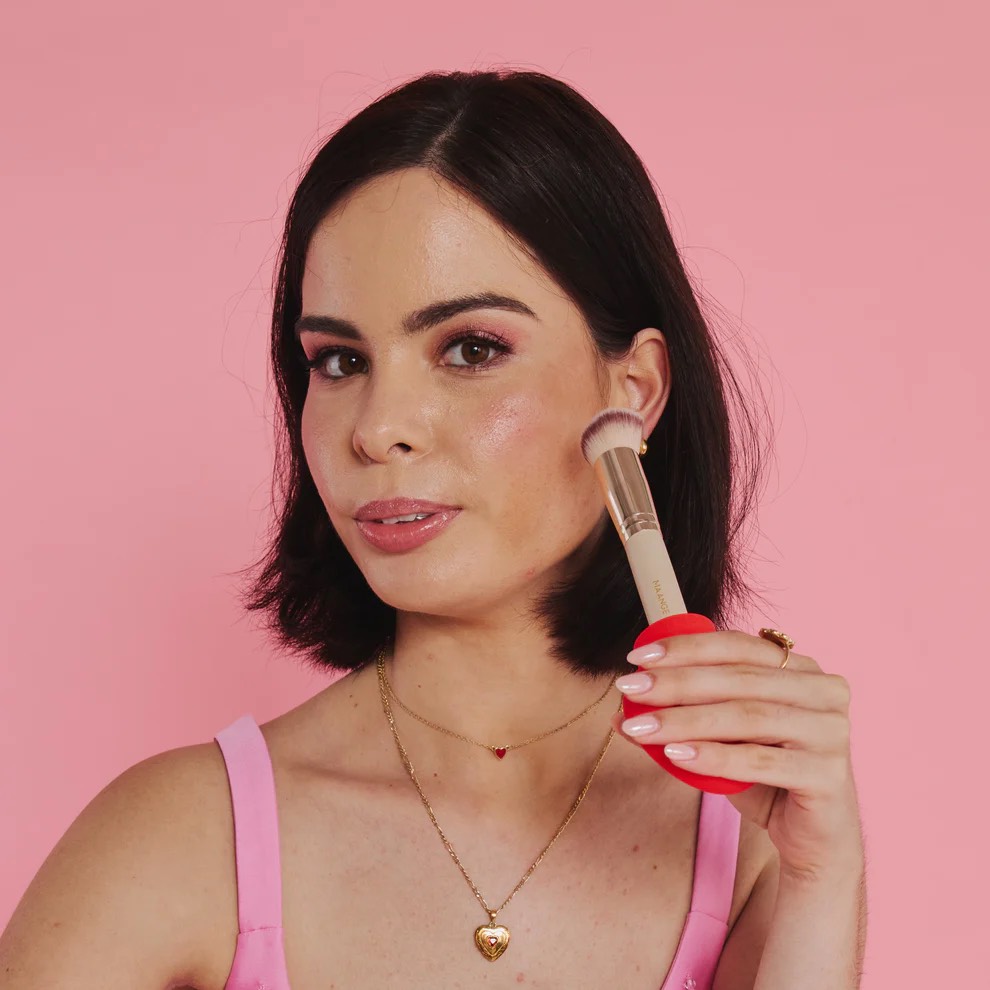 Woman applying cosmetic tool to the side of her face