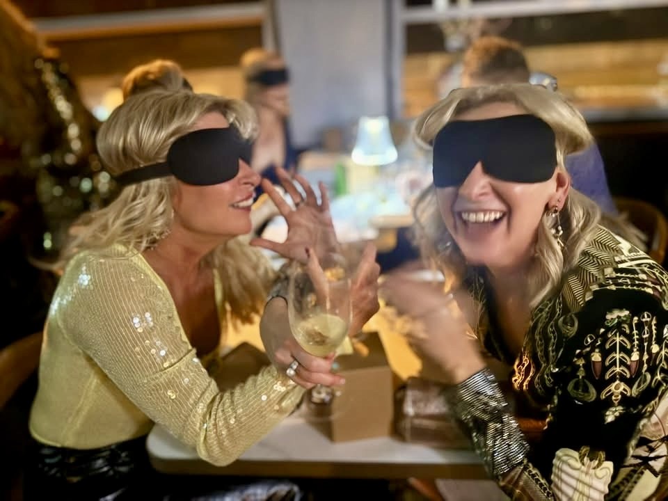 dinner in the dark 2 blindfolded women toasting with wine